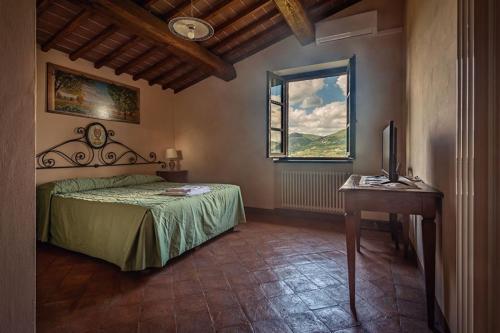 a bedroom with a bed and a desk and a window at Fonte Chiara in Gubbio