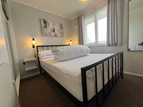 a bedroom with a bed with white sheets and a window at Beachcomber, Sunbeach, Scratby - Two bed chalet, sleeps 4, FREE Wi-Fi, FREE club passes, FREE swimming and pet friendly in Scratby