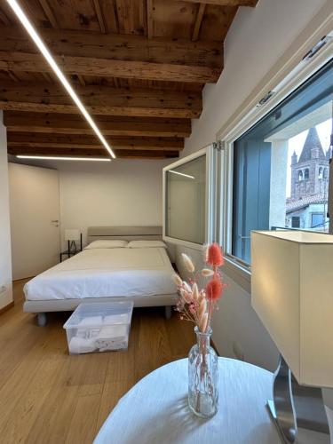 1 dormitorio con 1 cama y un jarrón de flores sobre una mesa en Residenza Della Samaritana, en Verona