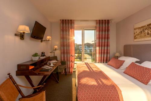 a hotel room with a bed and a desk and a window at Hôtel La Réserve in Saint-Jean-de-Luz