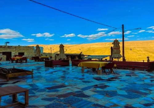 un patio de piedra con mesas y sombrillas en el desierto en bit mumia house & restaurant, en Kerak