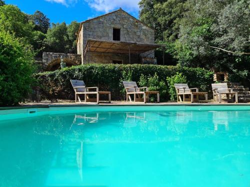 une piscine avec des chaises et une maison en arrière-plan dans l'établissement BERGERIE DE 1770 AVEC PISCINE, à Sartène