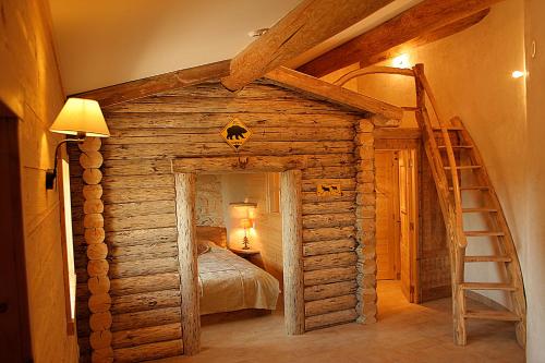 Dormitorio en cabaña de madera con cama y escalera en Valsoyo, en Upie