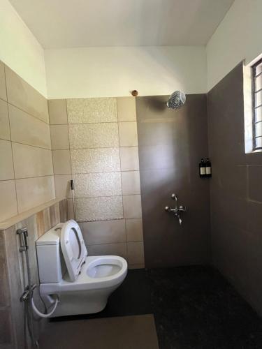 a bathroom with a toilet with the lid up at Red Rock Villa, Virajpet, Coorg in Virajpet