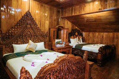 two beds in a room with wooden walls at Srey Krob Leak Resort in Battambang