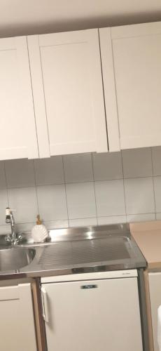 a kitchen with white cabinets and a sink and a refrigerator at Gli scogli a due passi in Portovenere