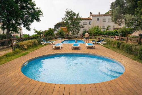 una gran piscina con tumbonas y un hombre de pie junto a ella en Kampaoh Calella de Palafrugell en Palafrugell