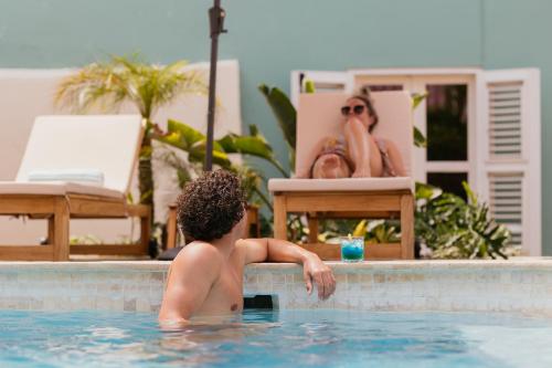un hombre en una piscina con una bebida en Pietermaai Oasis, en Willemstad