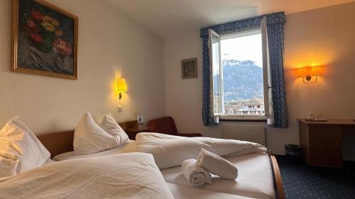 a hotel room with two beds and a window at Hotel Du Lac in Interlaken