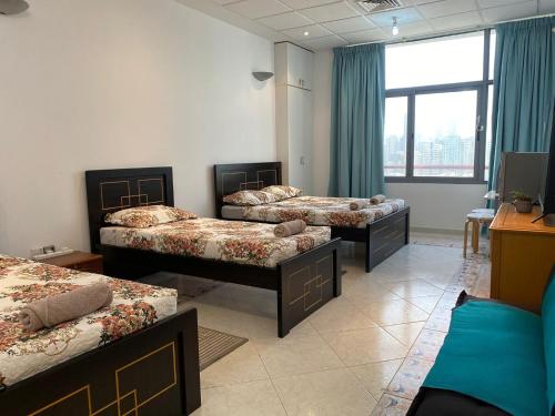 a room with three beds and a window at J & F Homestay - Abu Dhabi in Abu Dhabi