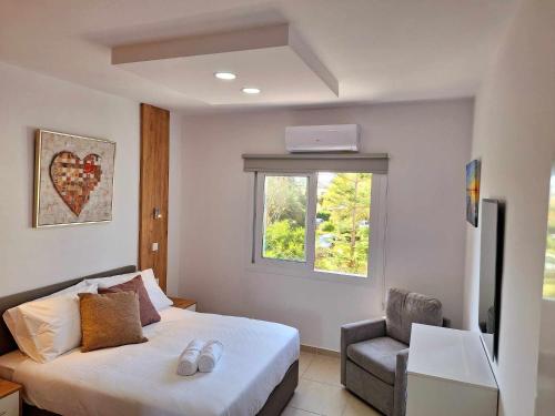 ein Schlafzimmer mit einem Bett, einem Stuhl und einem Fenster in der Unterkunft Stylish Apt Kato Paphos Close to Beach & Vibrant Harbor Life in Paphos City