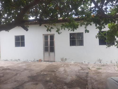 - un bâtiment blanc avec trois fenêtres et une porte dans l'établissement Casa de Veraneio Praia do Porto, à Pôrto das Cabras