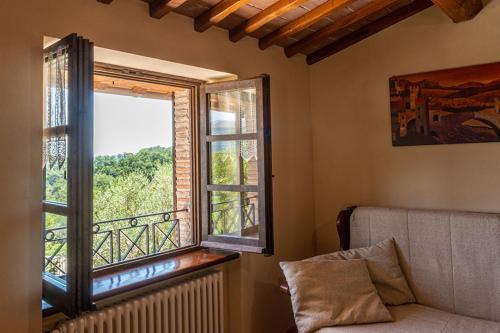 a room with a window and a couch and a balcony at Fonte Chiara in Gubbio