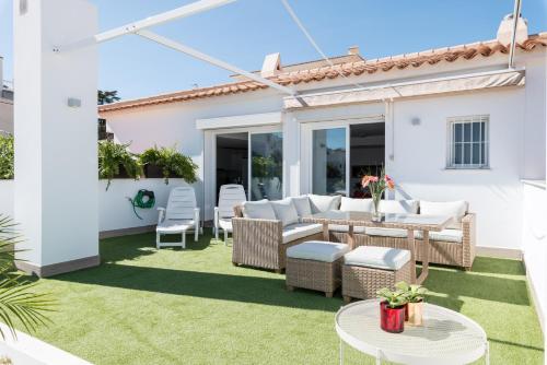 a patio with wicker furniture on a green lawn at Atico Altea17 by Vero in Altea