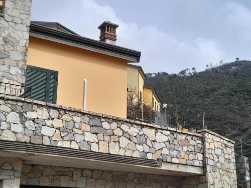 a building with a stone wall with a mountain in the background at Hotel Villa Argentina in Riomaggiore