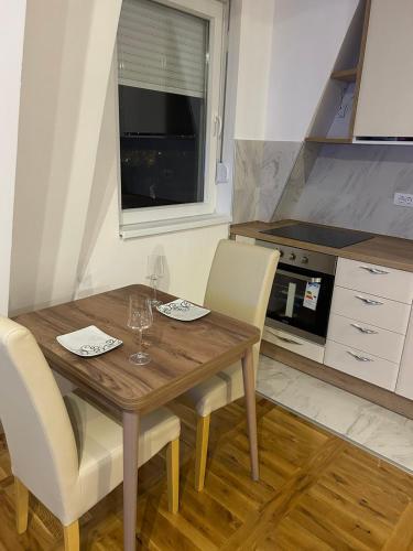 a kitchen with a wooden table and white chairs at Apartman Comfort Beograd in Belgrade