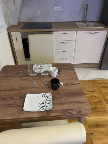 a wooden table with wine glasses and a laptop on it at Apartman Comfort Beograd in Belgrade
