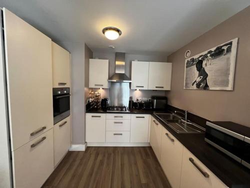 a kitchen with white cabinets and a sink in it at Riverside one bedroom flat in Bridge of Allan