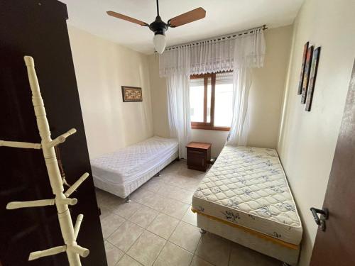 ein Schlafzimmer mit zwei Betten und einem Fenster in der Unterkunft Apartamento a uma quadra da praia in Capão da Canoa