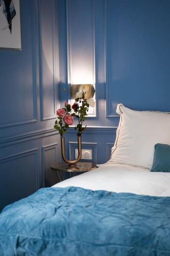 a blue bedroom with a bed and a vase of flowers at Le secret d'Ondine - Centre ville in Aix-les-Bains