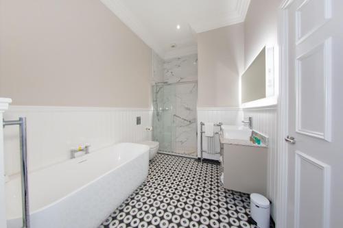 biała łazienka z wanną i umywalką w obiekcie Commodore Hotel w mieście Cobh