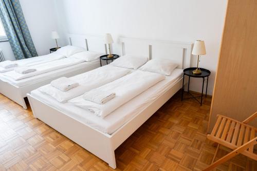 2 weiße Betten in einem Zimmer mit 2 Lampen in der Unterkunft Central Living Apartments - Staatsoper in Wien