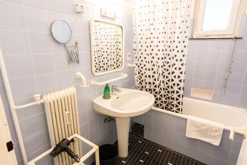 a blue tiled bathroom with a sink and a tub at Central Living Apartment Opera in Vienna