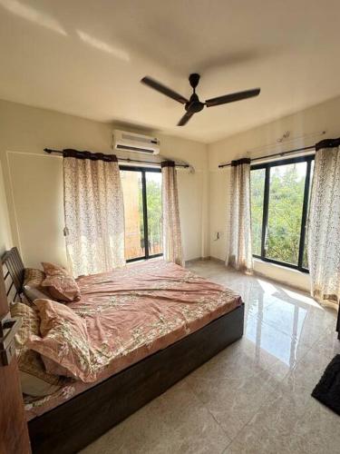 a bedroom with a large bed in a room with windows at Granthika’s House in Harnai