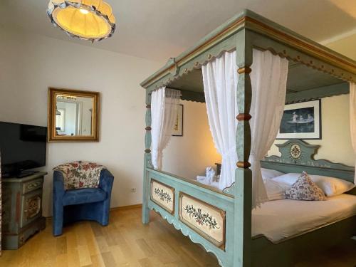 a bedroom with a canopy bed and a blue chair at Rosenhof am See Ferienwohnung Enzian in Thiersee
