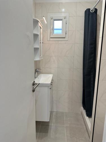 une salle de bain blanche avec un lavabo et une douche dans l'établissement Paris - Drancy, à Drancy