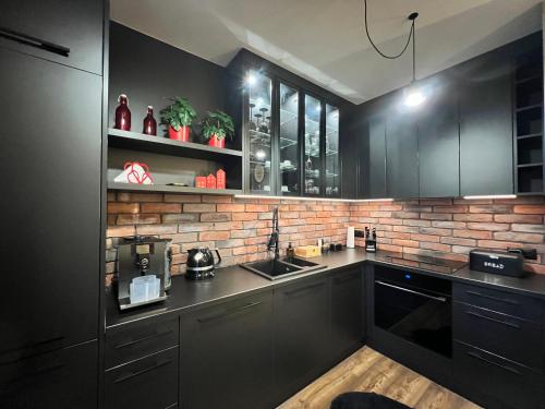 a kitchen with black cabinets and a brick wall at Silesia Apartments B129 in Ustroń