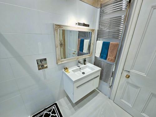 a white bathroom with a sink and a mirror at Merchant's View - Luxury Seaside Designer Retreat in Rothesay