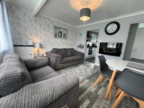 a living room with a couch and a table at 170, Two bed Chalet on Sunbeach Holiday Park - Sleeps 5, pet friendly, bed linen and towels included plus Wi-Fi included - only 300m from the beach! in Scratby