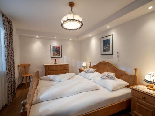 Un dormitorio con una gran cama blanca y una lámpara de araña. en Rosenhof am See, en Thiersee