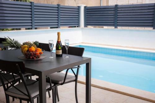 una mesa con copas de vino y un bol de fruta junto a la piscina en Apartments Gabrieri, en Dubrovnik