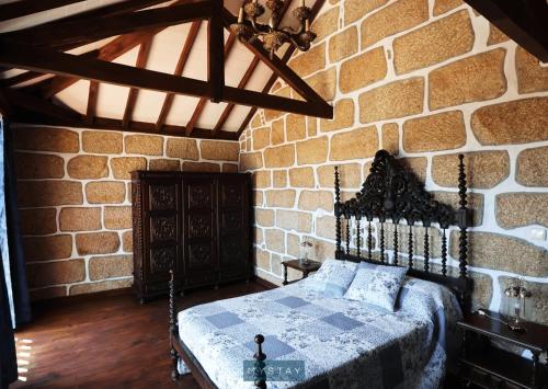 a bedroom with a bed in a stone wall at MyStay - Casa do Vale JC in Vila Nune