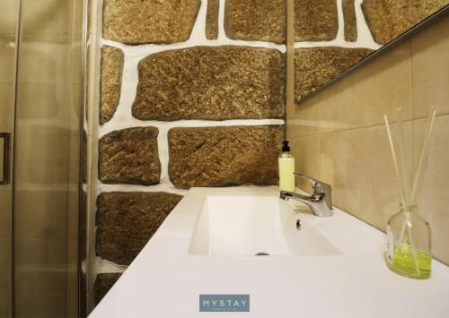baño con lavabo y pared de piedra en MyStay - Casa do Vale JC, en Vila Nune