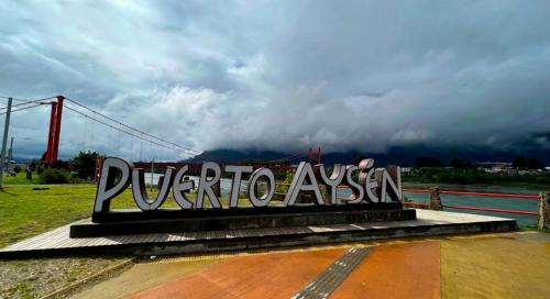 Znak ze słowem Puerto Argentina przed mostem w obiekcie Barrio estación w mieście Puerto Aisén