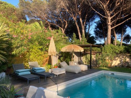 un patio avec des chaises et un parasol à côté d'une piscine dans l'établissement La Vagabonde, à Saint-Tropez