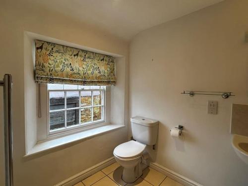 a bathroom with a toilet and a window at Partridge in Lyddington