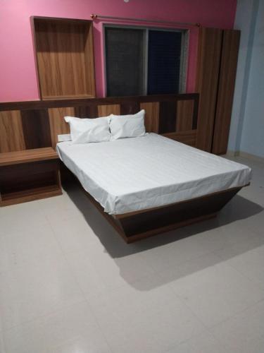 Hotel Jyoti في Madhubani: غرفة نوم بسرير وملاءات بيضاء ونافذة