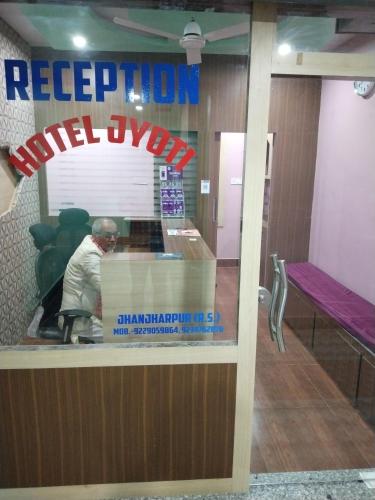 a reflection of a man in the window of a restaurant at Hotel Jyoti in Madhubani