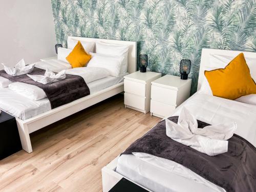 2 bedden in een kamer met witte en gele kussens bij Gemütliches Apartment in zentraler Lage in Hamburg Alsterdorf für bis zu 7 Personen in Hamburg
