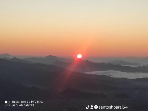 a sunset on a mountain with the sun rising over the clouds at Lake View Lodge Sarangkot in Pokhara