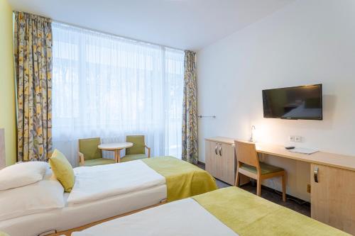ヤーヒモフにあるHotel Běhounekのベッド2台とデスクが備わるホテルルームです。