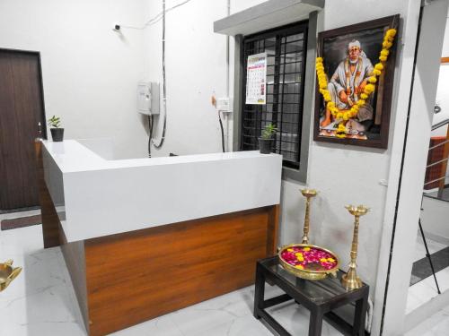 a bathroom with a white sink and a bowl on a table at Hotel Sai Sneha in Shirdi