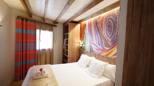 um quarto com uma cama branca e uma pintura na parede em EL DELFÍN VERDE RESORTS - Platja d'Aro em Platja  d'Aro