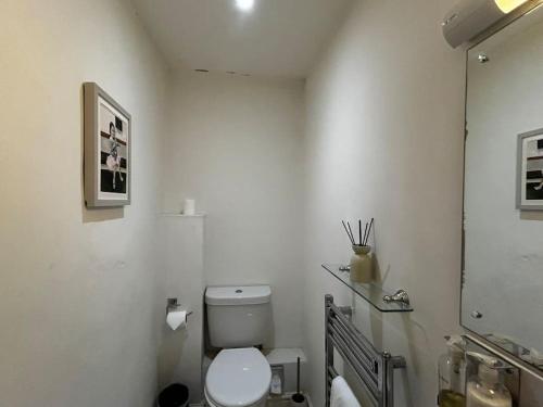 a white bathroom with a toilet and a mirror at Quail in Lyddington