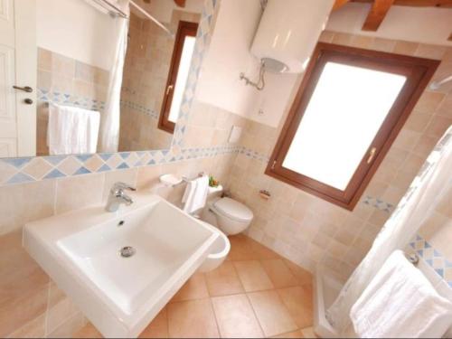 a bathroom with a sink and a toilet and a window at Apartment in Vignola Mare near Sandy Beach in Vignola Mare