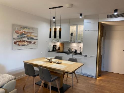 a kitchen and dining room with a wooden table and chairs at Apartament Premium PINEA 316 in Pobierowo